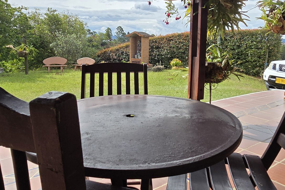 Mesa y mecedoras de madera en la terraza cubierta de La Amalita, mirando hacia el jardín